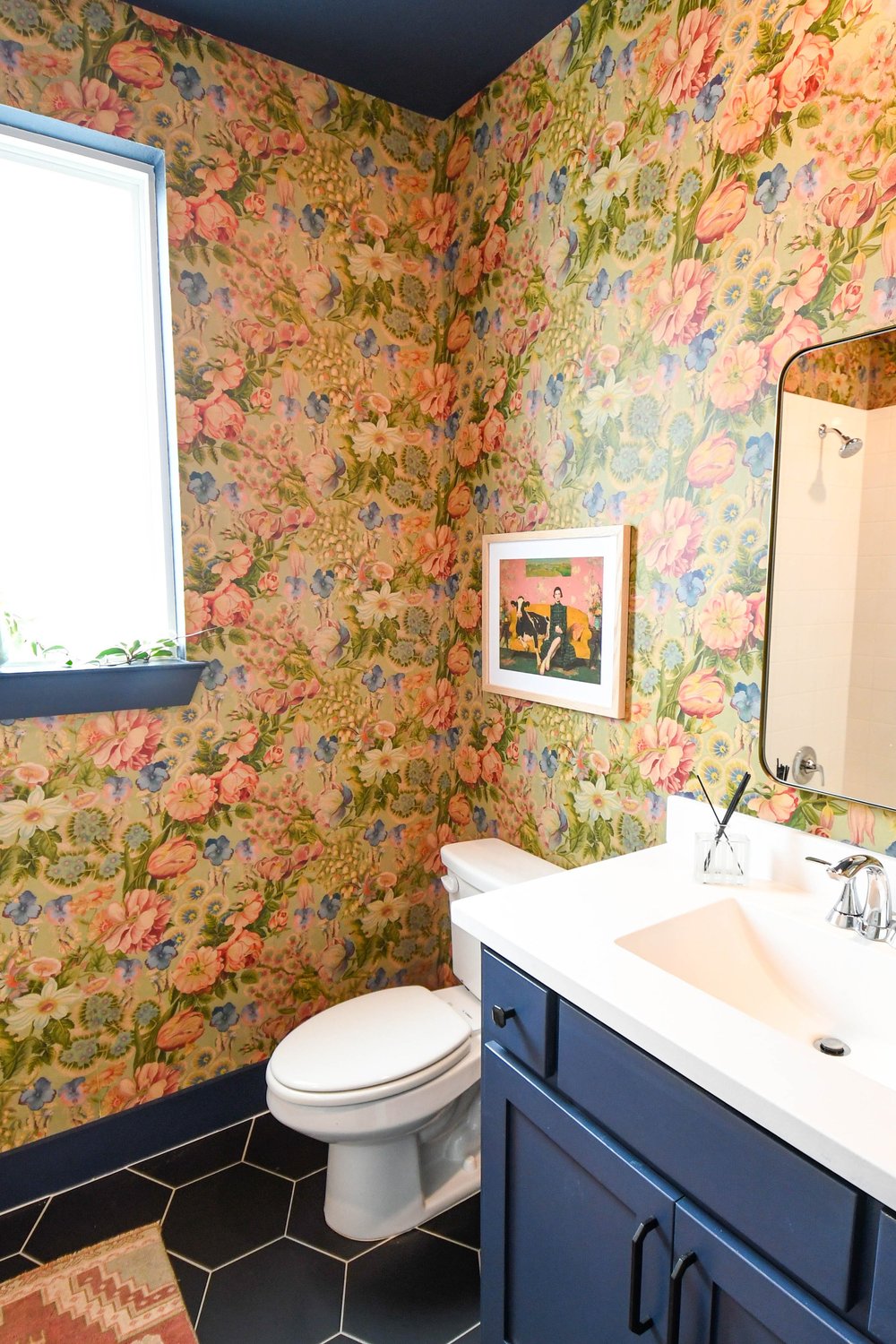 Vanity and toilet corner where the wallpaper meets the navy ceiling above the window