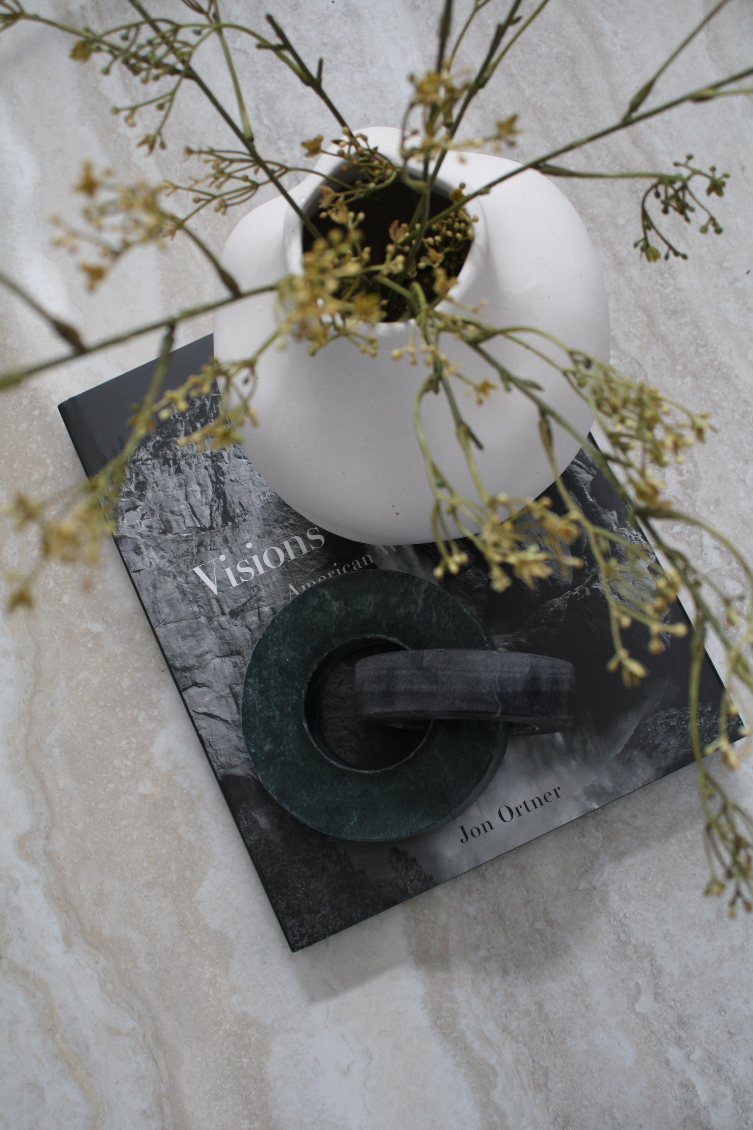A marble surface styled with a design book, a round vase and dried flowers