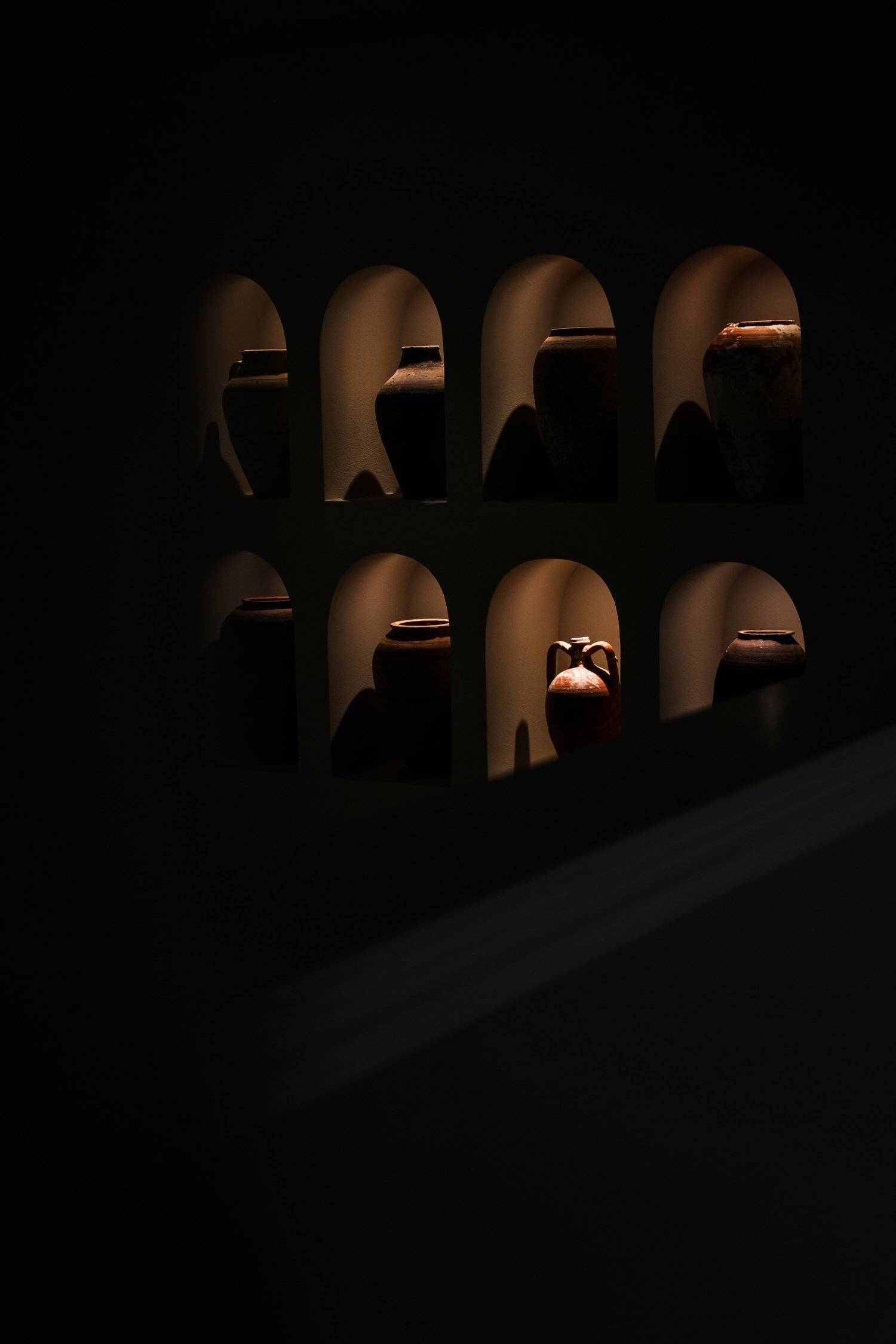 A dark wall of lit arched display niches